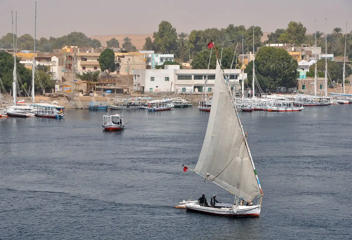 Berge du Nil à Assouan avec une felouque et des bateaux amarrés